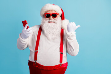 Fototapeta na wymiar Portrait of his he nice attractive cheerful cheery glad confident white-haired Santa using device demonstrating copy space 5g app isolated bright vivid shine vibrant blue color background