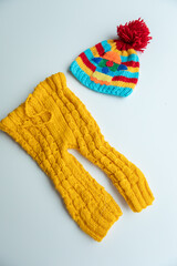 Various colors and types of cotton clothing, knitted newborn clothes and newborn hats on a white background.