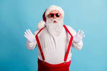 Fototapeta na wymiar Portrait of his he nice attractive cheery funky playful humorous white-haired Santa pulling suspenders having fun fooling isolated over bright vivid shine vibrant blue color background