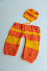 Various colors and types of cotton clothing, knitted newborn clothes and newborn hats on a white background.