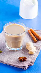 Masala chai tea on a linen napkin. Traditional indian drink - masala tea with various spices. Glass of masala tea on a blue background