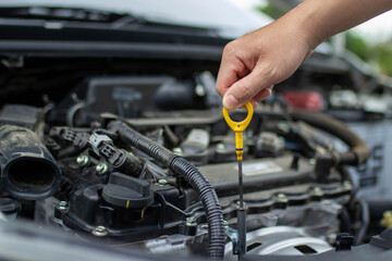 Auto repair center, an auto mechanic's hand, is checking the engine oil level so the car is ready to go long distances.