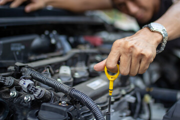 Obraz premium Auto repair center, an auto mechanic's hand, is checking the engine oil level so the car is ready to go long distances.