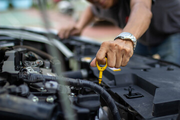 Auto repair center, an auto mechanic's hand, is checking the engine oil level so the car is ready...