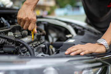 Auto repair center, an auto mechanic's hand, is checking the engine oil level so the car is ready to go long distances.