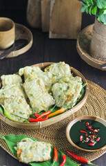 Tempe Mendoan or Indonesian traditional fried tempeh, one of popular street food made from tempeh, deep fried, served with sambal or chili. Dark wooden background.