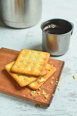 Cracker and coffee on the wooden chopping board on the table