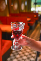 Woman hand holding wine glass inside. Eating out in restaurant concept.