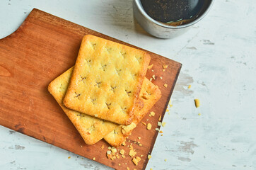 Cracker and coffee on the wooden chopping board on the table