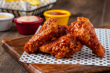 Baked chicken wings with sesame and sauce on wooden background
