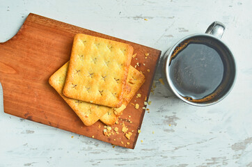 Cracker and coffee on the wooden chopping board on the table