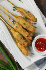 Sempol Ayamor Chicken Fried Skewer, Indonesian  Traditional street food made from fried chicken meat and egg, on white plate , served with chili sauce. Dark wooden background.