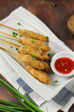 Sempol Ayamor Chicken Fried Skewer, Indonesian  Traditional street food made from fried chicken meat and egg, on white plate , served with chili sauce. Dark wooden background.