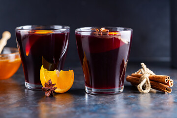 Mulled wine on a dark background. Two cups of autumn mulled wine and ingredients. Christmas hot drink with wine and honey
