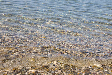 the surface of the water of the Adriatic Sea with a small wave on a pebble beach