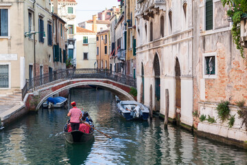 Fototapeta na wymiar ITALY, VENICE - 24 JULY, 2019: Men gondoliers drive gondolas with tourists in Venice in Italy.