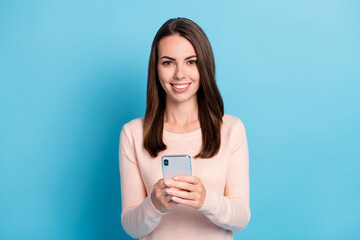 Photo of positive cheerful girl hold cellphone wear pastel pullover isolated over blue color background
