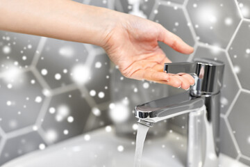 hygiene, health care and safety concept - close up of woman's hand opening water tap in winter over snow