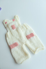 Various colors and types of cotton clothing, knitted newborn clothes and newborn hats on a white background.