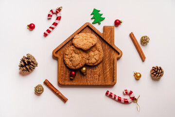 Cookies lie on a Board in the form of a house surrounded by Christmas toys and decorations, photo from above on a white background, copyspace