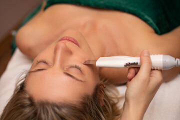 Naklejka premium Close-up Of Woman Getting Facial Hydro Microdermabrasion Peeling Treatment At Cosmetic Beauty Spa Clinic. Face Skin Care. Hydra Vacuum Cleaner. Exfoliation, Rejuvenation And Hydratation. Cosmetology.