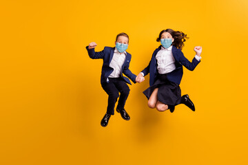 Fototapeta na wymiar Full length photo of small little crazy ecstatic schoolkids jumping wear uniform respirator isolated vibrant yellow color background