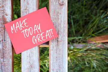 Make today great motivational quote written on a red paper on a wooden fence