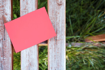 Blank empty red paper sign mock up on a wooden fence