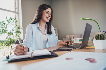 Photo of lovely business woman pen write diary look screen netbook wear specs shirt in home office indoors