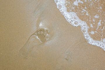 single footprint in the sand washed by wave