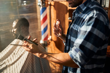 Male barber disinfecting hairdressing tools before haircut