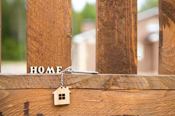 Keychain of wooden figure house on fence with key and inscription in English letters 