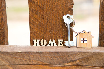 Keychain of wooden figure house on fence with key and inscription in English letters 