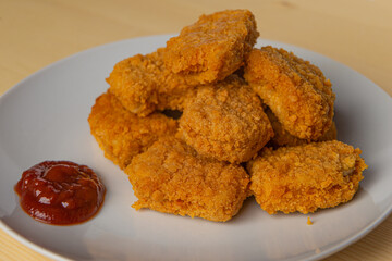 Chicken nuggets on a white plate, with ketchup
