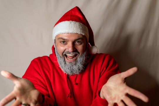 Santa Claus stands in front of the camera with his arms wide open and invites you to a hug with a big smile