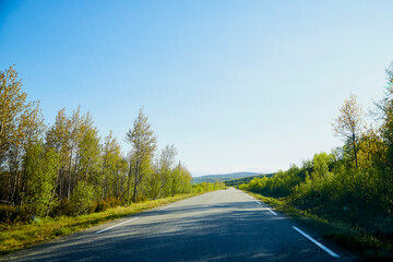 View from car windscreen with stripe relief to highway, tundra and blue sky in norht region at a sunny day