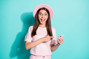 Photo of impressed girl point finger smartphone wear pink t-shirt sunhat isolated over teal color background