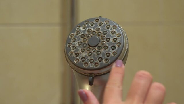 Closeup view 4k video of old shower head with calcified limescale. Woman touching dirty surface going to clean surface.