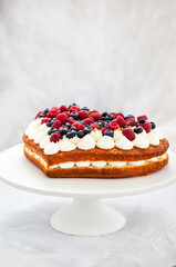 Delicious homemade heart shaped vanilla cake decorated with cream and fresh berries