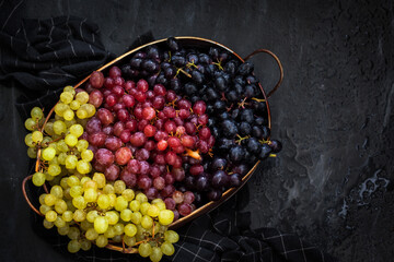 White, red and black fresh autumn grapes on dark background, top view