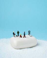 Creative layout made with miniature people cleaning snow on white soap. Minimal winter activity...