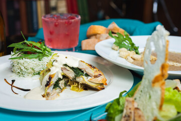 Fillet of white fish sea bass, cod stuffed with greens and rice on the table in the restaurant.