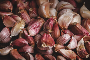 Garlic background.
Close-up photograph of a group of garlic cloves on dark brown wood.
