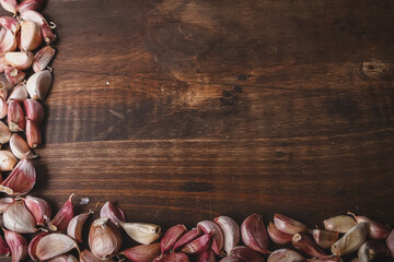 Garlic cloves frame.
Dark brown wooden board with half frame of garlic cloves. Space for text.