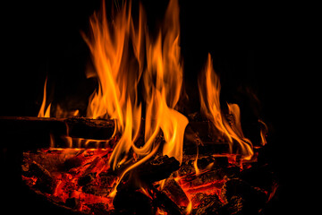 Fototapeta premium Orange flames of fireplace in dark with hot coals