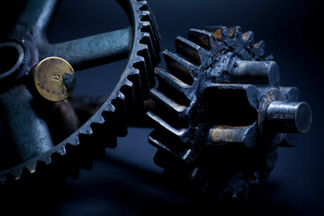 Studio still of heavy greasy machine gears on dark background. Selective focus, shallow depth of field.