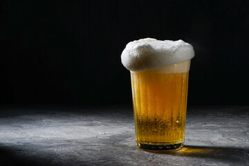 full faceted glass with beer and with big froth on gray background

