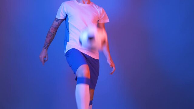 tatooed european man training soccer indor blue and red lights