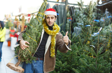 Portrait of joyful man choosing toys and Christmas tree at fair outdoor