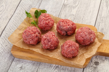 Raw meatball over wooden background